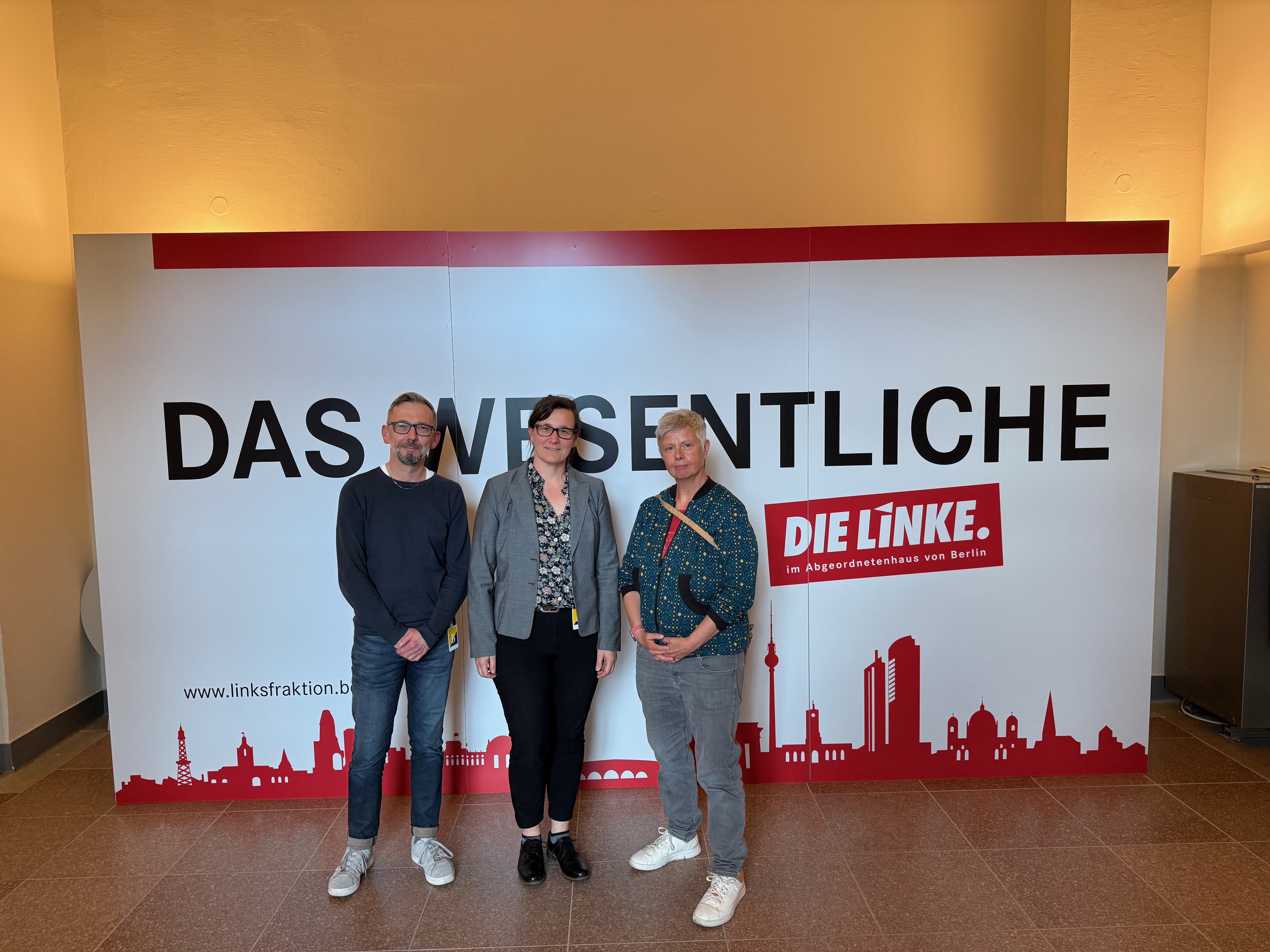Anne Wistuba, Carsten Welp & Katina Schubert stehen vor einem Banner von der Partei Die Linke